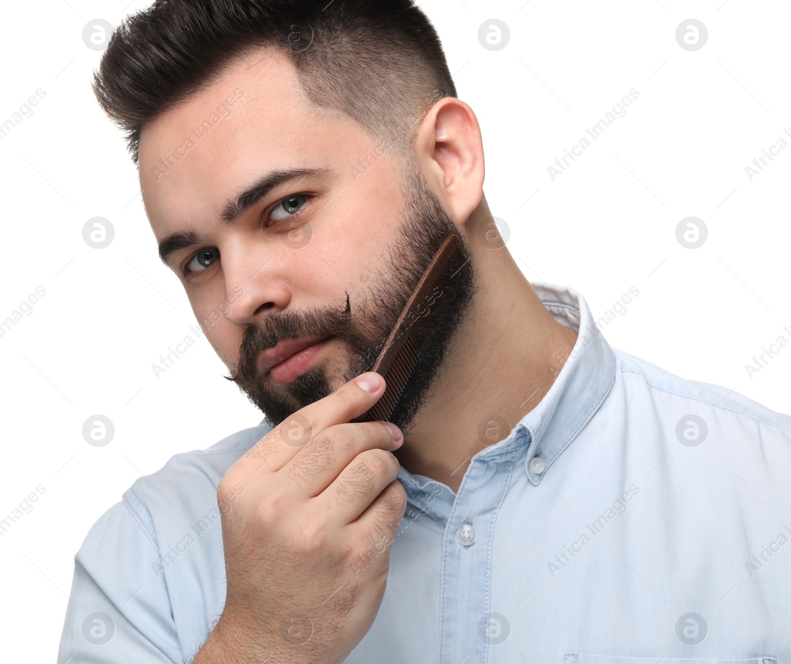 Photo of Handsome young man combing beard on white background