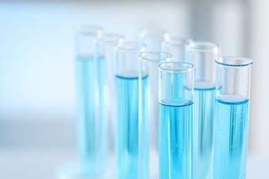 Photo of Test tubes with light blue liquid in laboratory, closeup. Space for text