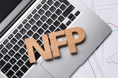 Wooden letters NFP, laptop and charts on table, flat lay