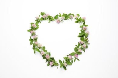 Photo of Heart shaped frame of beautiful clover flowers with green leaves on white background, top view. Space for text