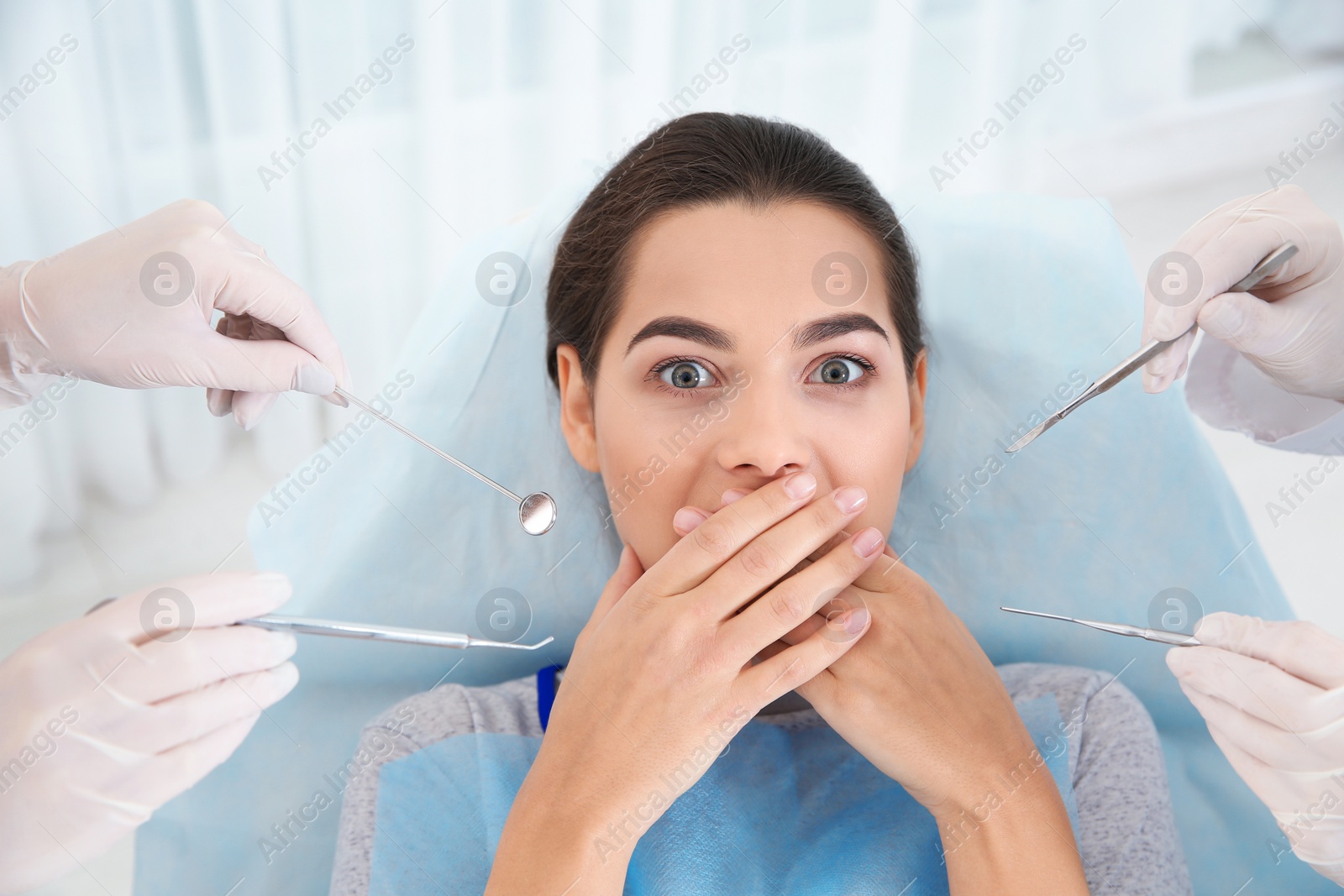 Photo of Young woman scared of dental examination in clinic