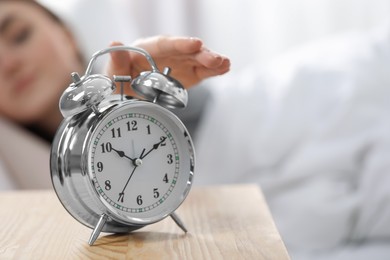 Young woman turning off alarm clock at home in morning, closeup. Space for text