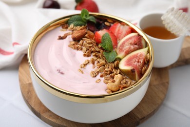 Bowl with yogurt, fruits and granola on white tiled table, closeup