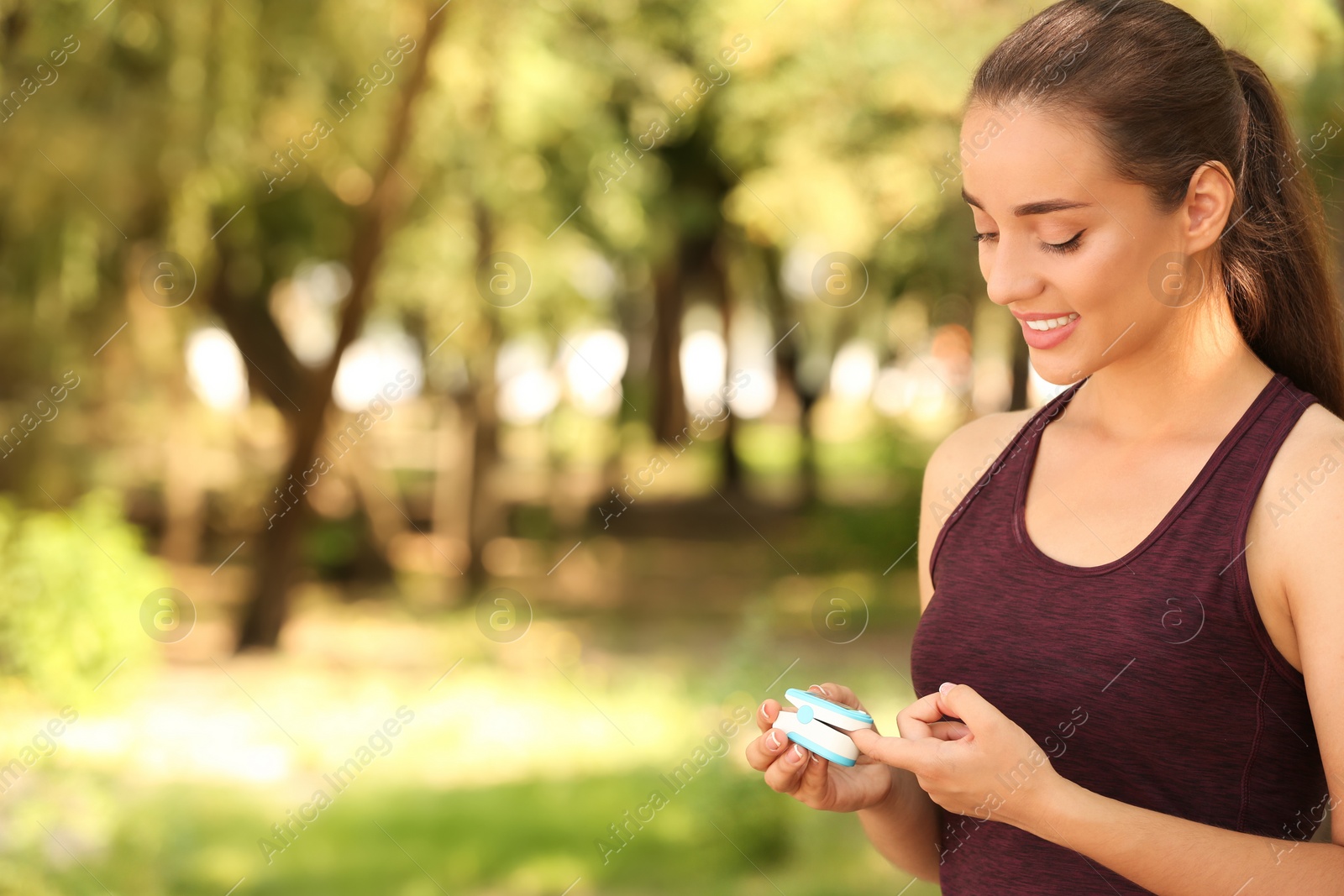 Photo of Young woman checking pulse outdoors on sunny day