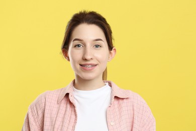 Portrait of smiling woman with dental braces on yellow background