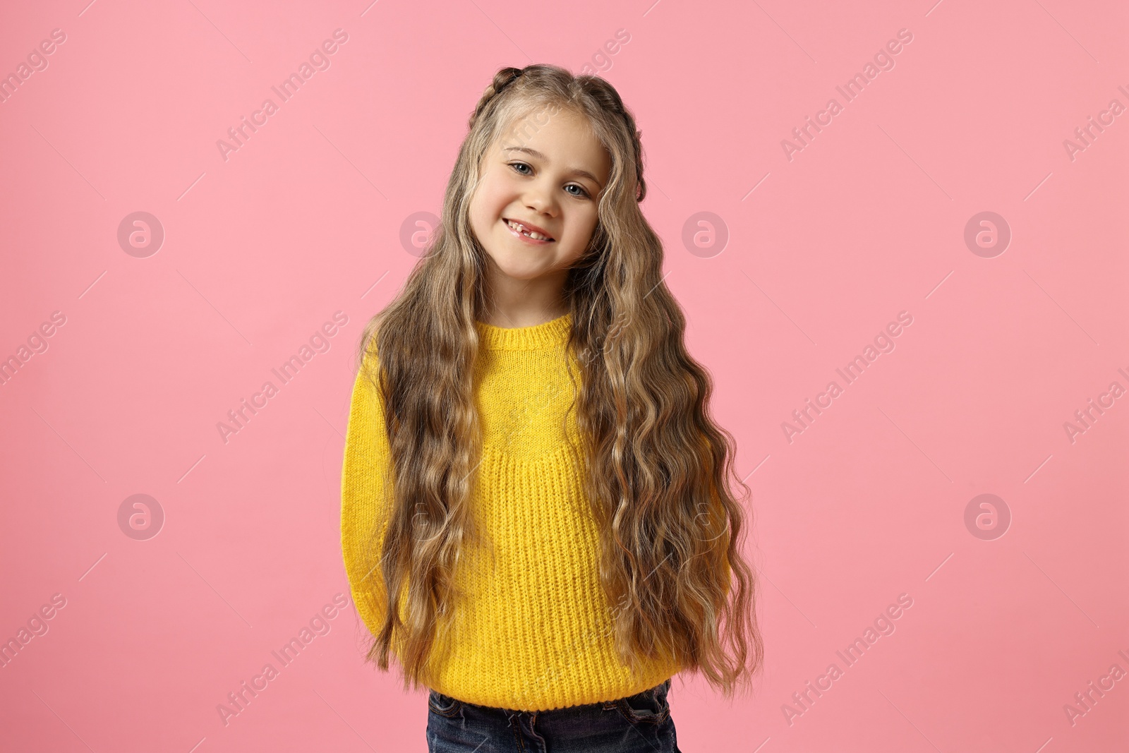 Photo of Cute little girl with braided hair on pink background