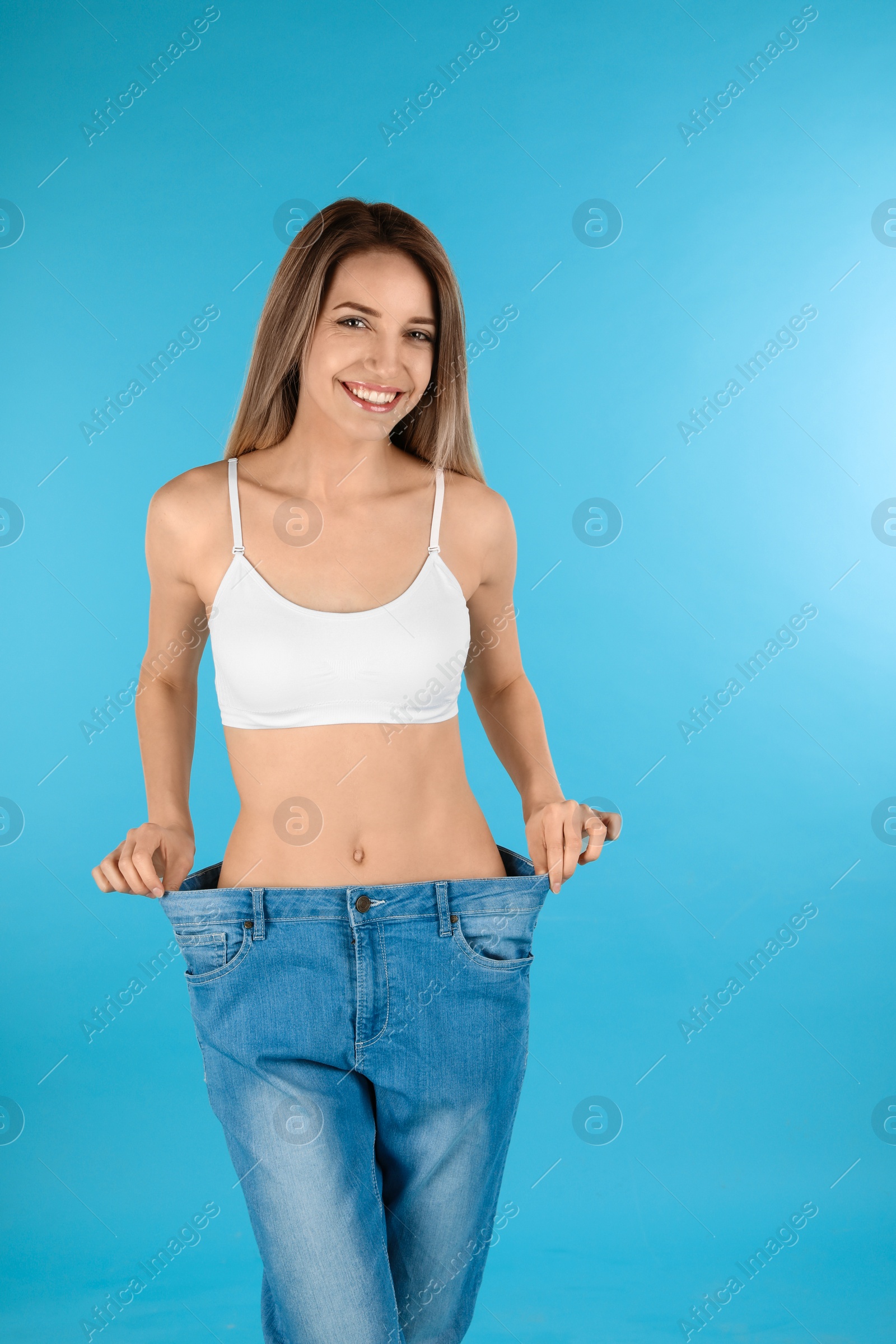 Photo of Slim woman in oversized jeans on color background. Perfect body