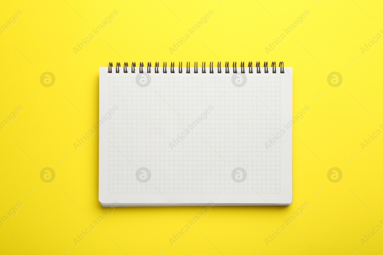 Photo of One notebook on yellow background, top view. Space for text