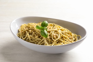 Photo of Plate of delicious basil pesto pasta on white background