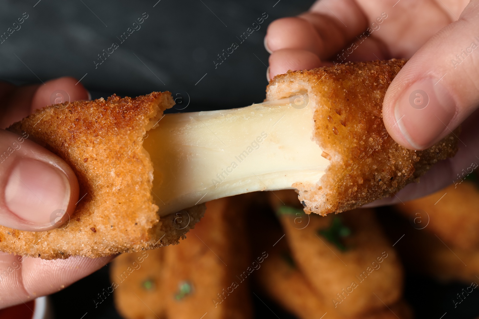 Photo of Woman holding broken cheese stick over table, top view