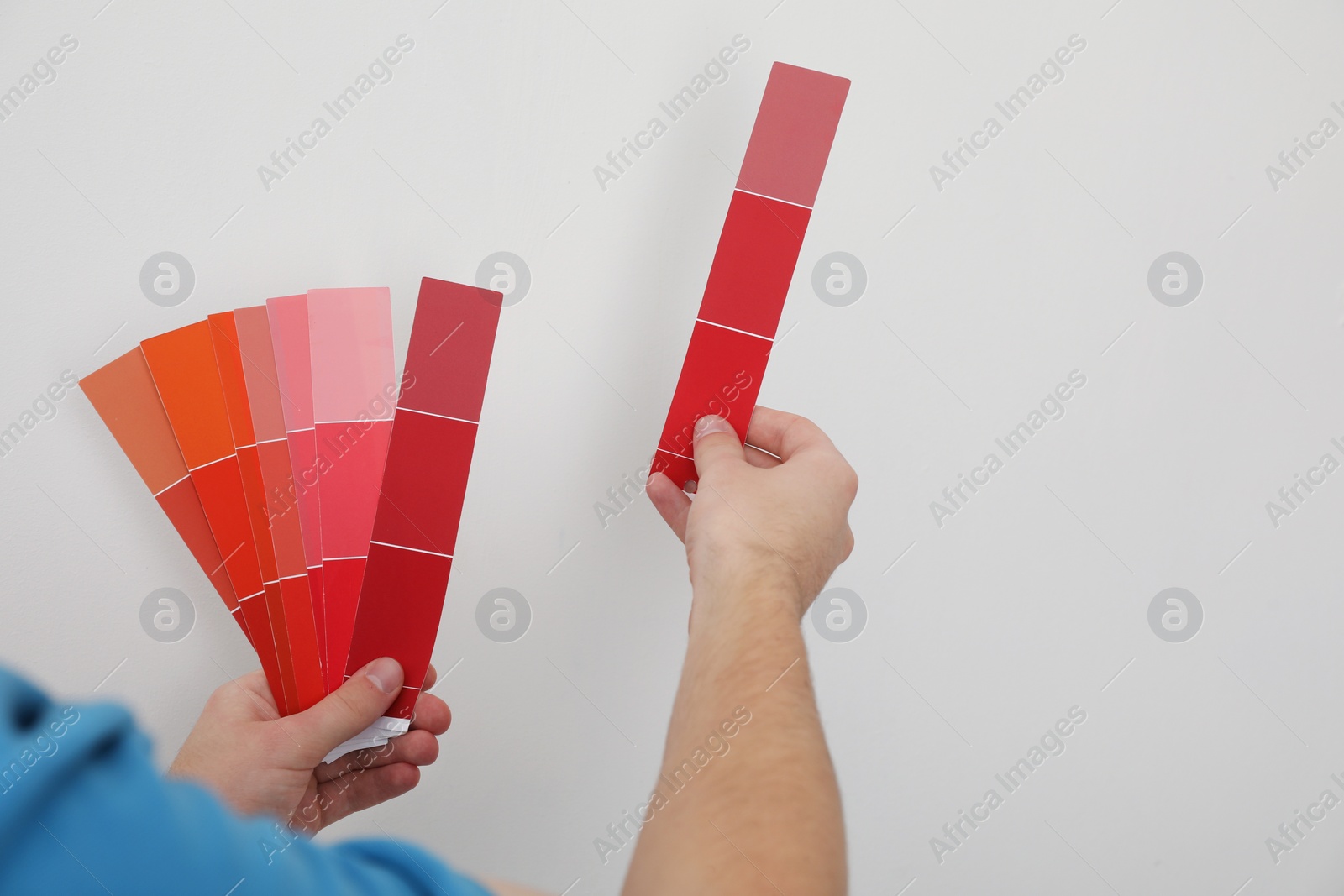 Photo of Man with palette choosing color for painting wall indoors, closeup. Interior design