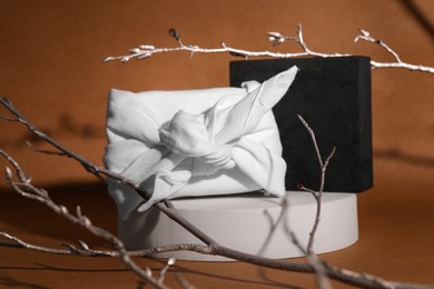 Photo of Furoshiki. Things packed in fabric and painted branches on brown background