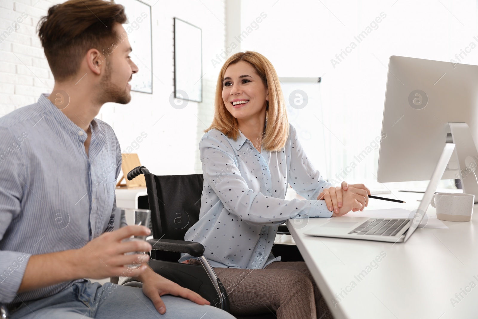 Photo of Woman in wheelchair with her colleague at workplace