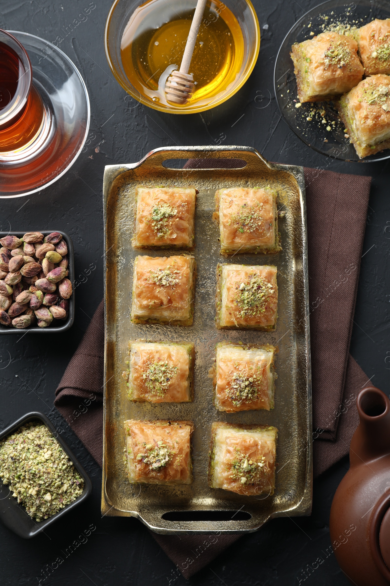 Photo of Delicious fresh baklava with chopped nuts served on grey textured table, flat lay. Eastern sweets