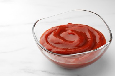 Bowl of tasty ketchup on white marble table, closeup