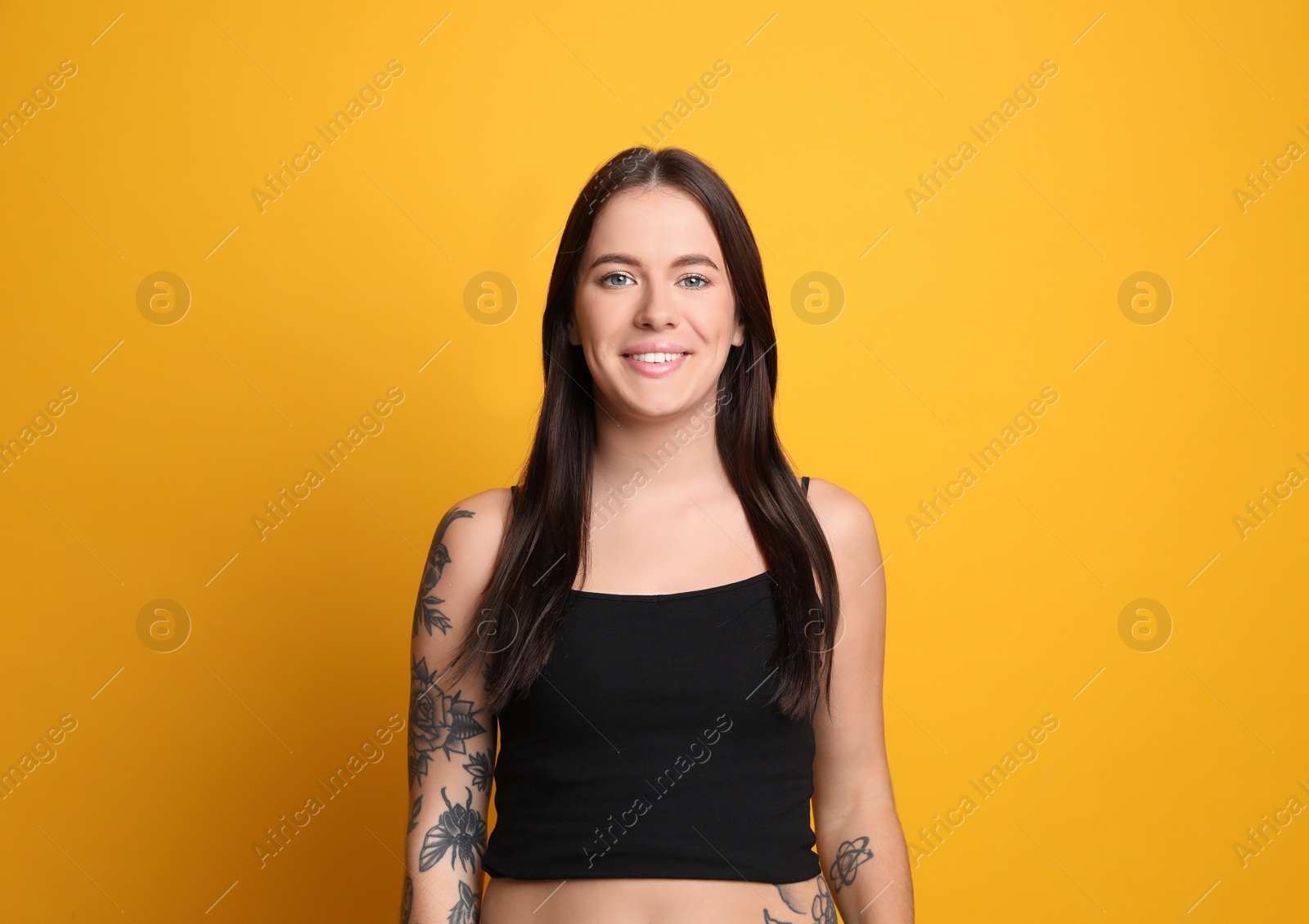 Photo of Beautiful woman with tattoos on arms against yellow background