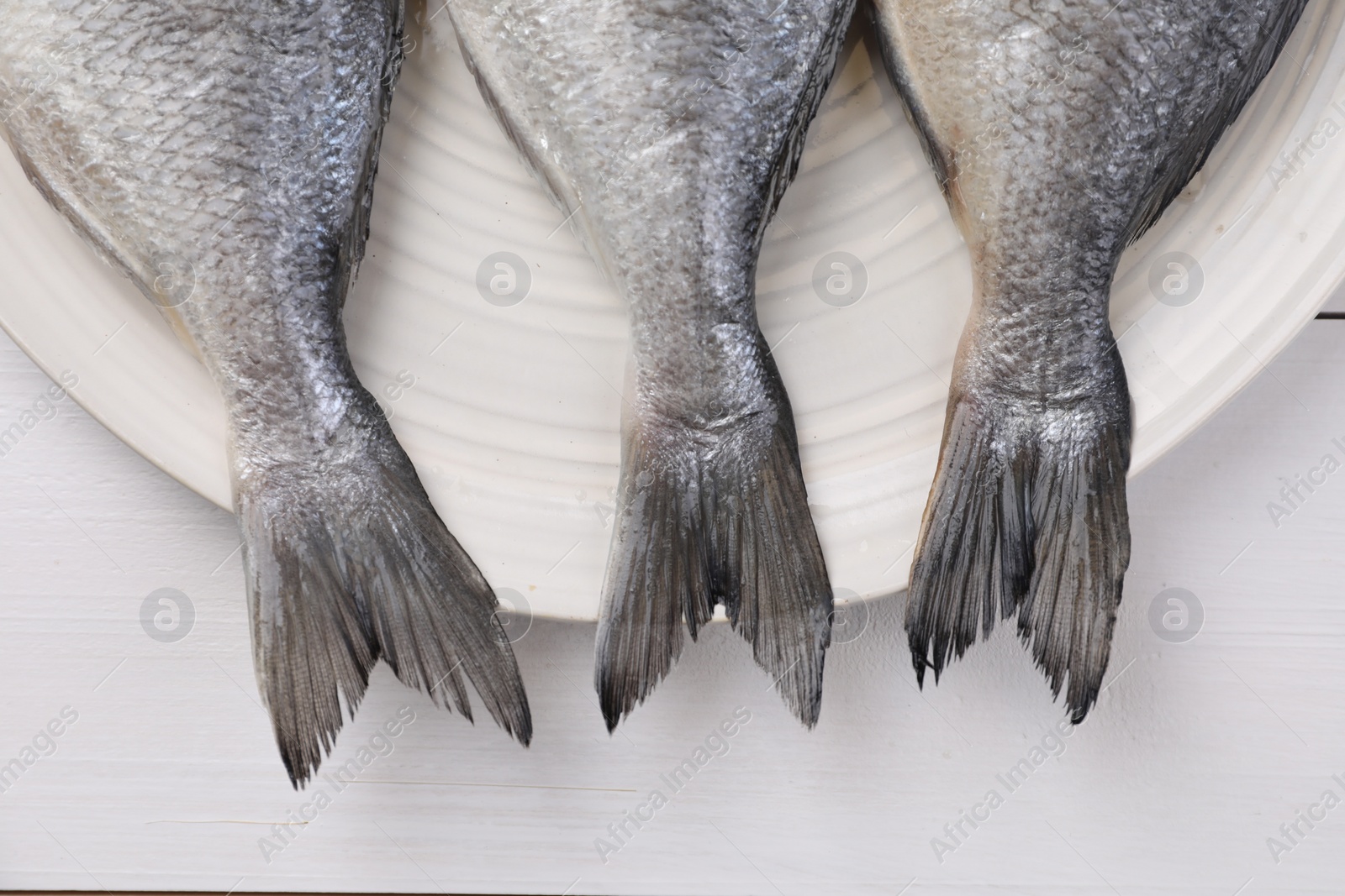 Photo of Fresh raw dorado fish on white wooden table, top view