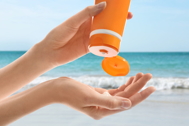 Image of Young woman applying sun protection cream near sea, closeup