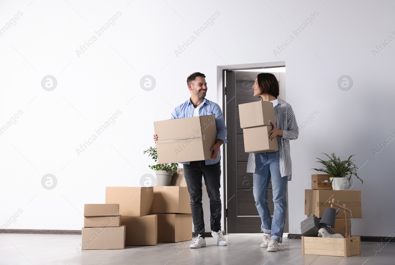 Photo of Happy couple with moving boxes entering in new apartment