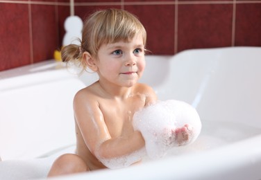 Little girl bathing in tub at home