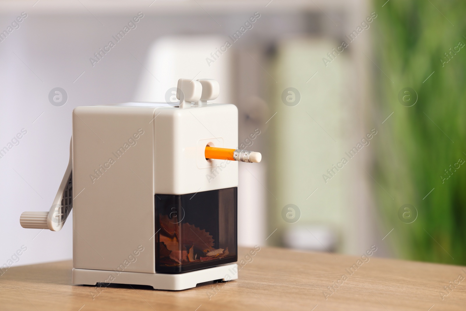 Photo of Mechanical sharpener with pencil on wooden table indoors. Space for text