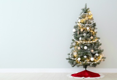 Photo of Decorated Christmas tree with red skirt indoors, space for text