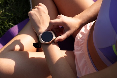Photo of Woman checking fitness tracker after training outdoors, closeup