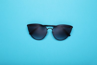 Photo of Stylish sunglasses on light blue background, top view
