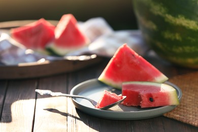 Photo of Slices of ripe watermelon with spoon on wooden table outdoors