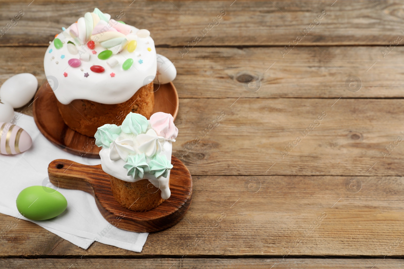 Photo of Traditional Easter cakes and painted eggs on wooden table, space for text