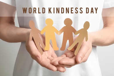 World Kindness Day. Woman holding paper figures of people on light background, closeup