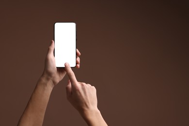 Photo of Man using smartphone with blank screen on brown background, closeup. Mockup for design