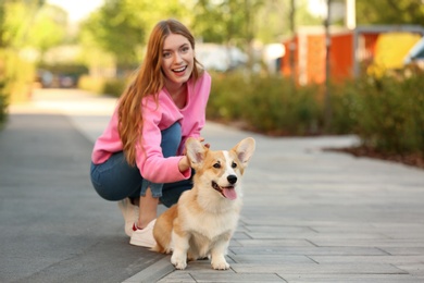 Young woman with her adorable Pembroke Welsh Corgi dog in park