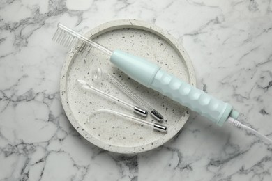 Photo of Tray with darsonval and different nozzles on white marble table, top view