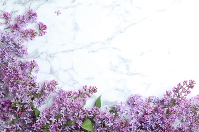 Photo of Blossoming lilac flowers on marble table, flat lay. Space for text