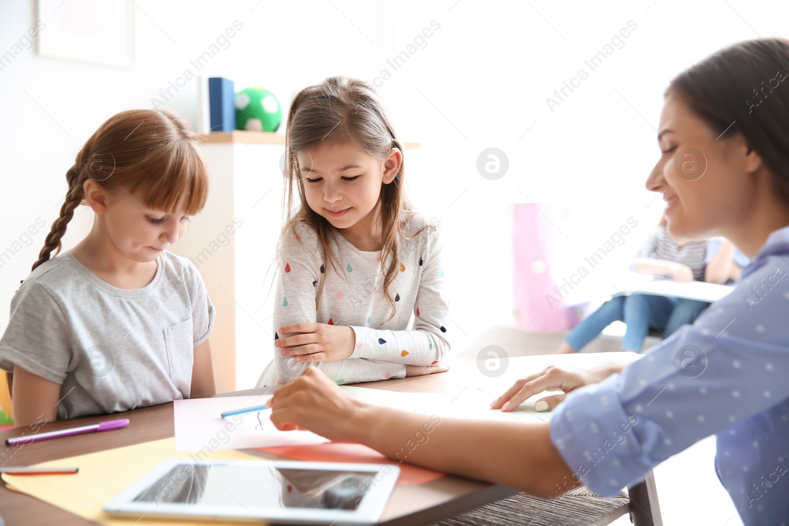 Photo of Cute little children with teacher in classroom at school