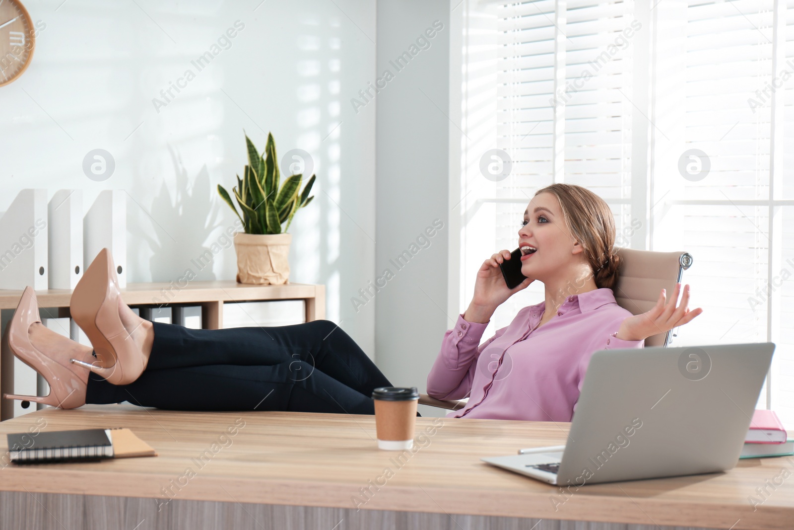 Photo of Lazy office worker talking on phone at desk indoors