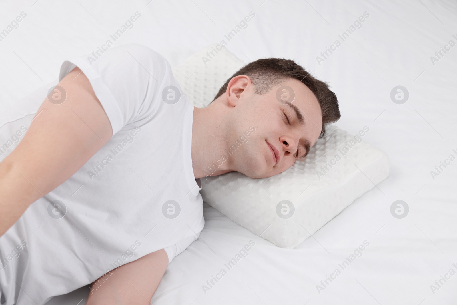 Photo of Man sleeping on orthopedic pillow in bed