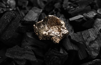 Photo of Shiny gold nugget on coals, closeup view