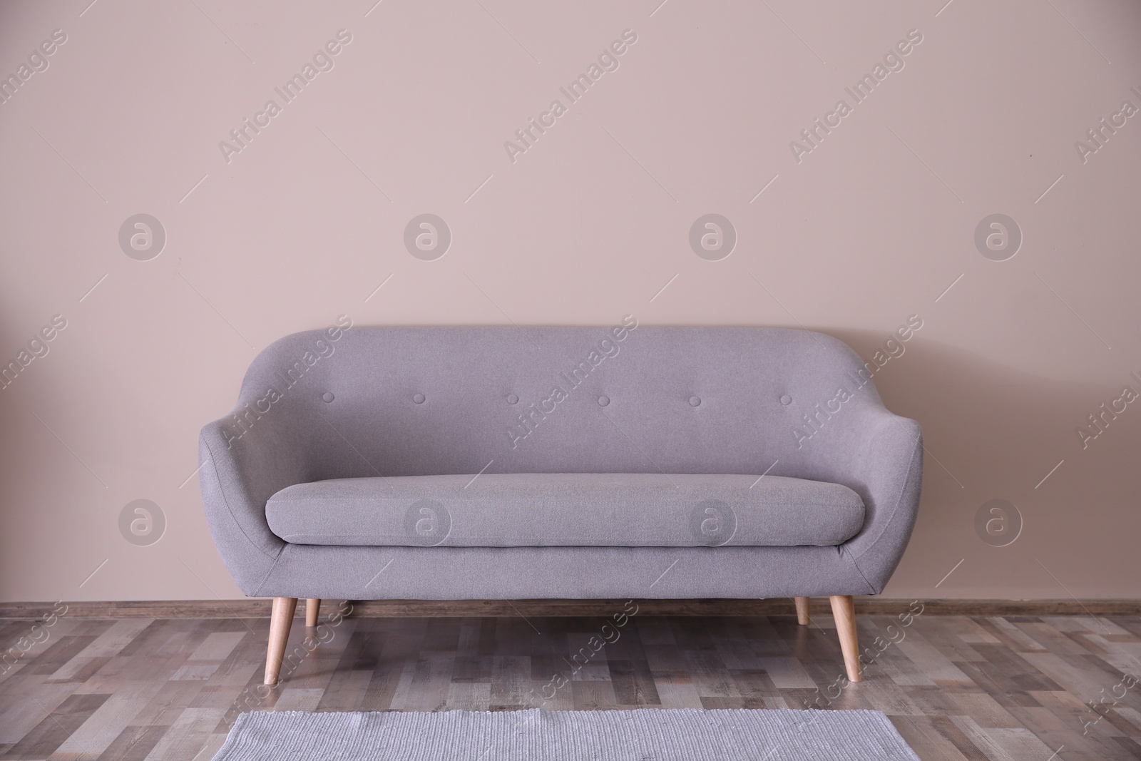 Photo of Simple living room interior with comfortable sofa near color wall. Copy space text