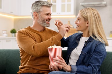 Happy affectionate couple with popcorn spending time together on sofa at home. Romantic date