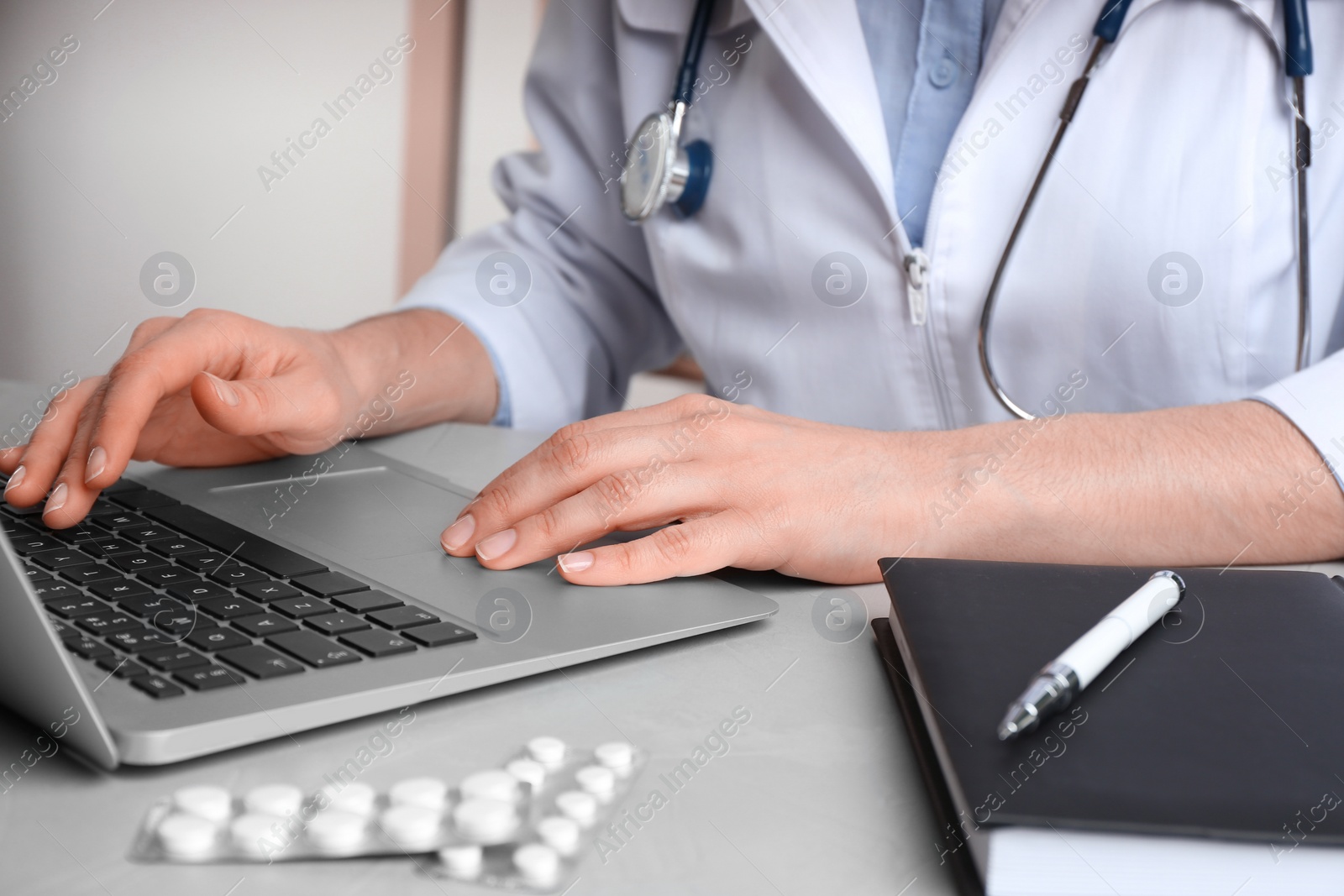 Photo of Doctor working with laptop at desk in office, closeup. Medical service