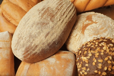 Photo of Different freshly baked breads as background, view from above