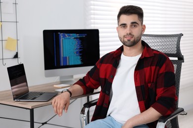 Happy young programmer working at desk in office