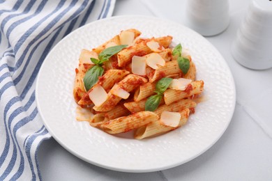 Tasty pasta with tomato sauce, cheese and basil on white table