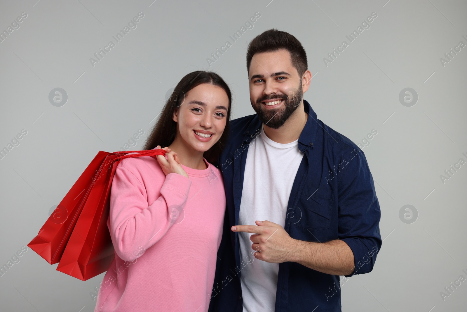 Photo of Happy couple with shopping bags on grey background