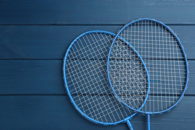 Photo of Rackets on blue wooden table, flat lay with space for text. Badminton equipment