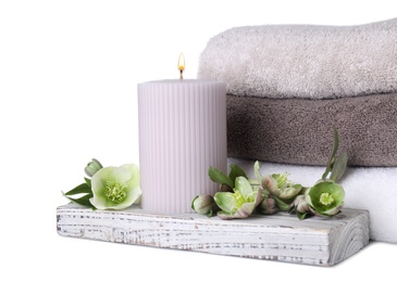 Photo of Composition with towels, candle and flowers isolated on white. Spa treatment