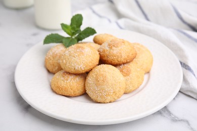 Photo of Tasty sweet sugar cookies and mint on white marble table, closeup