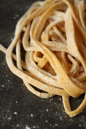 Photo of Uncooked homemade pasta on dark grey table, closeup